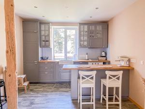 a kitchen with gray cabinets and white stools at Kolka in Kolka