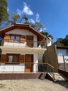 una casa con balcón y escaleras delante en Chalé vista das montanhas, en Monte Verde