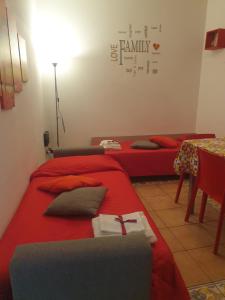 a room with two beds with red sheets and a table at Casa Palazzo Reale in Palermo