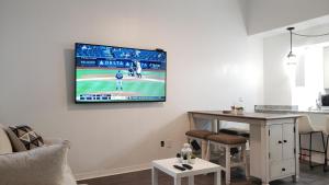 a living room with a tv hanging on a wall at Discover Luxury Condo Steps Away from Celebration Pointe and I-75! in Gainesville