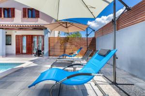 twee blauwe stoelen en een parasol naast een zwembad bij Casa Vian in Pula