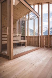 een grote houten kamer met ramen en een tafel bij Schuischta Mountain Apartments in Sesto