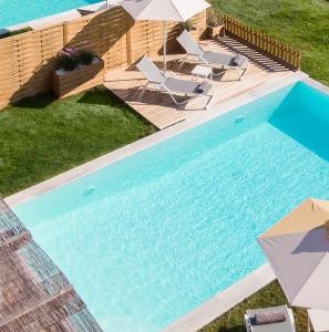 a swimming pool with chairs and umbrellas next to it at Reiki Villas in Ereikoússa