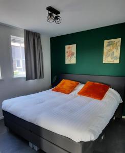 a bedroom with a large bed with two orange pillows at Hof Babel in Domburg