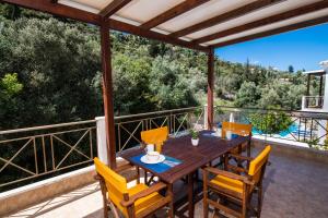 a wooden table and chairs on a balcony with a view at Delphinus Villa Nefeli in Agios Nikitas