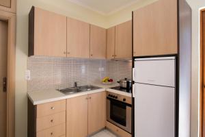 a kitchen with wooden cabinets and a white refrigerator at Delphinus Villa Nefeli in Agios Nikitas