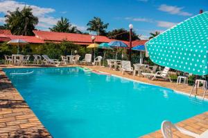 a swimming pool with chairs and umbrellas and a pool at Pousada das Acerolas in Penedo