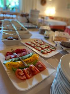 una mesa cubierta con platos de comida con tomates y pepinos en Pension Schmidt, en Podersdorf am See