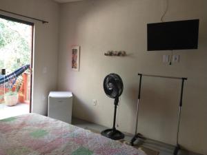 een slaapkamer met een ventilator en een flatscreen-tv bij Casa Di Gaya in Cabo Frio