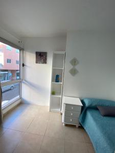 sala de estar con sofá azul y ventana en Nice rooms in a shared apartment in the centre of Corralejo, en Corralejo