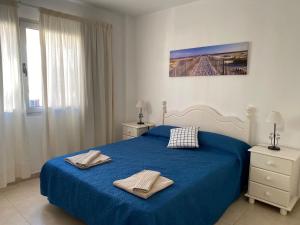 sypialnia z niebieskim łóżkiem i 2 ręcznikami w obiekcie Nice rooms in a shared apartment in the centre of Corralejo Habitaciones en piso compartido w Corralejo