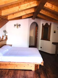 - une chambre avec un grand lit blanc dans une pièce dotée de plafonds en bois dans l'établissement Hotel Mountain Resort, à Commezzadura