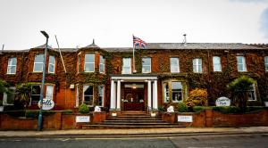 un edificio de ladrillo rojo con una bandera en la parte delantera en Cumbria Park Hotel en Carlisle