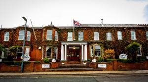 a red brick building with a flag on the front at Cumbria Park Hotel in Carlisle