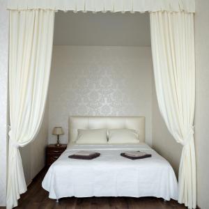 a bedroom with a white bed with white curtains at Апартаменты в Одессе in Odesa