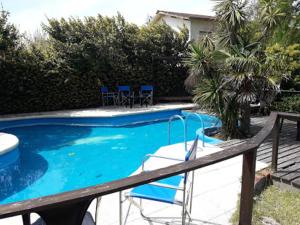 a swimming pool with blue chairs in a yard at Hotel Capri in Villa Gesell