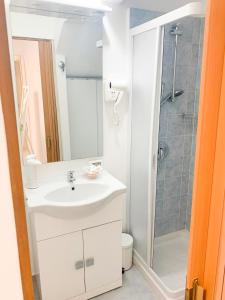 W łazience znajduje się biała umywalka i prysznic. w obiekcie RockSea Apartments w Cefalù