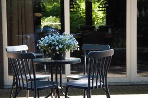 une table et des chaises avec un vase de fleurs. dans l'établissement bosbungalow Ruighenrode, à Lochem