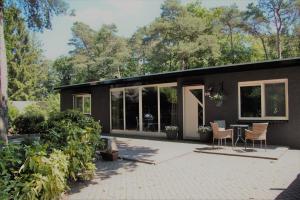 a house with a patio with a table and chairs at bosbungalow Ruighenrode in Lochem