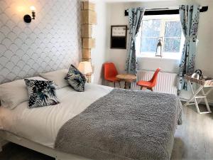 1 Schlafzimmer mit einem Bett mit 2 Stühlen und einem Fenster in der Unterkunft Cotswold Merrymouth Inn in Bourton on the Water