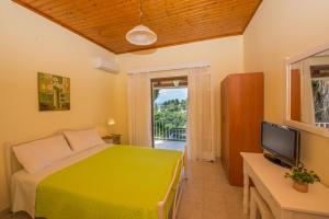 a bedroom with a green bed and a television at Nicoles Houses Arillas Corfu in Arillas