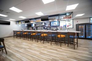 a bar in a restaurant with a row of stools at Holiday Inn St Louis - Creve Coeur in Saint Louis