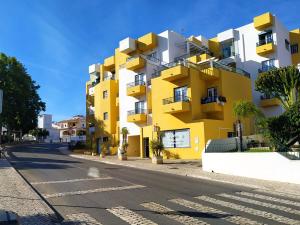 ein gelbes und weißes Gebäude an der Straßenseite in der Unterkunft Apartment My Site Alvor in Alvor