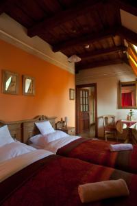 two beds in a room with orange walls at St.Michael Panzió Lovaspark in Vasszentmihály