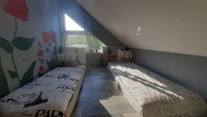 a attic bedroom with two beds and a window at Willa Zacisze apartament 12 in Kąty Rybackie