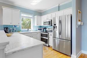 uma cozinha com armários brancos e uma geladeira de aço inoxidável em Cool Corner em Folly Beach