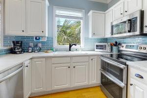 uma cozinha com armários brancos, uma pia e uma janela em Cool Corner em Folly Beach mais 16 fotografias