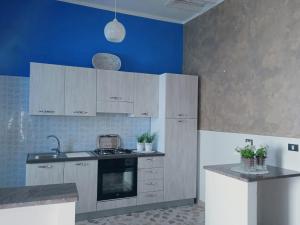 eine Küche mit weißen Schränken und einer blauen Wand in der Unterkunft Le Lamie in Sessa Cilento