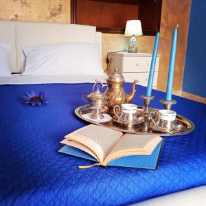Ein Tablett mit einem offenen Buch und einem Teeservice auf einem Bett in der Unterkunft Le Lamie in Sessa Cilento