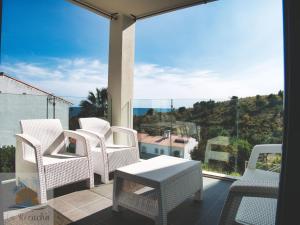 d'un balcon avec des chaises blanches, une table et une grande fenêtre. dans l'établissement 1minuto del mar ,vistas, Playa tranquila. Adaptado, à Benajarafe