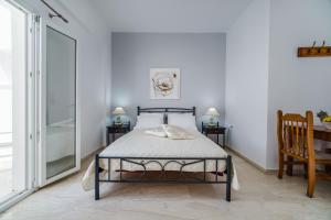 a bedroom with a bed and two tables and a chair at Stavros Villas in Karterados