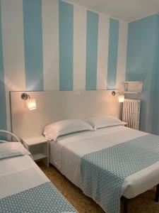 2 camas en un dormitorio con rayas azules y blancas en Hotel Del Golfo, en Laigueglia