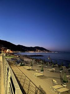 una playa con sillas y sombrillas y el océano en Hotel Del Golfo, en Laigueglia