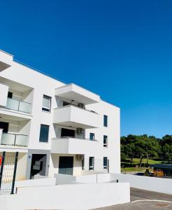 a white building with balconies on the side of it at Apartment Alexandra in Premantura