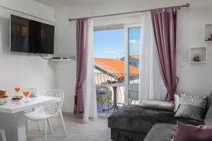 ein Wohnzimmer mit einem Sofa und einem Tisch sowie einem Balkon in der Unterkunft Hortenzija Apartments in Makarska