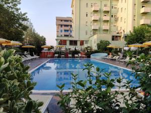 a large swimming pool with chairs and umbrellas at Hotel Prestigio in Cesenatico