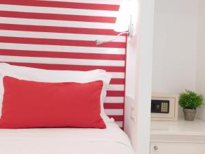 a red and white striped wall in a bedroom with a red pillow at Duomo Guest House in Sorrento