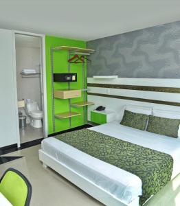 a bedroom with a bed and a green wall at Hotel Genova Prado in Barranquilla