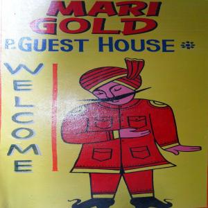 a sign with a man in a coat and a guest house at Marigold Guest House in Varanasi
