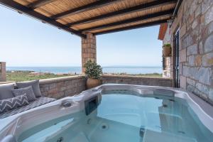 a hot tub on a patio with a view of the ocean at Polismata - Private Residences in Kardamili