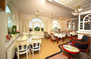 a dining room with tables and chairs in a restaurant at Pension Strandschloss Arielle in Börgerende-Rethwisch