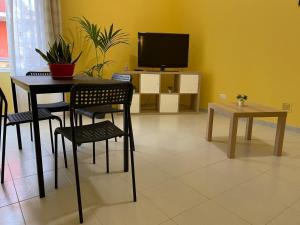 uma sala de jantar com mesa e cadeiras e uma televisão em Lu Cori di Sossu em Sorso