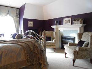 a bedroom with a bed and two chairs and a fireplace at The Beacon Inn at Sidney in Sidney