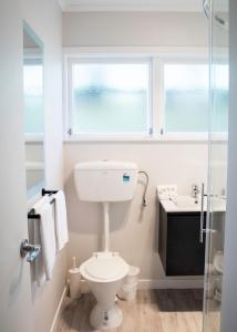 een badkamer met een toilet, een wastafel en een raam bij Rehutai Beach House in Paihia