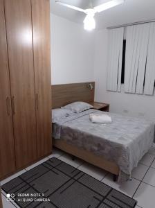 een slaapkamer met een bed en een houten kast bij Recanto chalenger in Campos dos Goytacazes