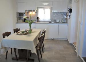 una cocina con mesa y sillas y una cocina con armarios blancos. en Rustico Gino, en Vairano